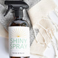 Bottle of Shiny Spray with a label on a textured surface