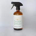 Bottle of Shiny Spray with Lemongrass & Sage scent on a white background