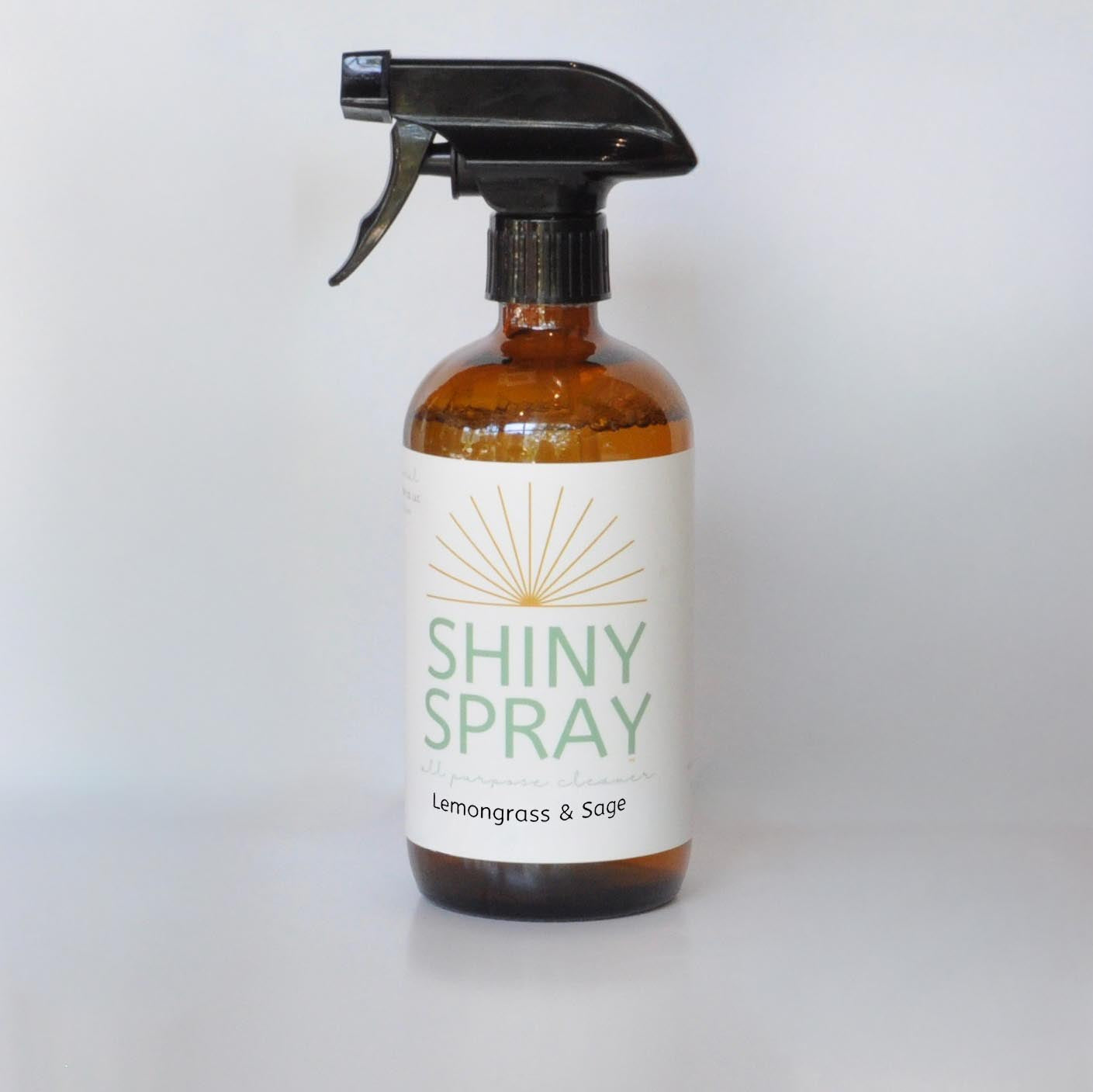 Bottle of Shiny Spray with Lemongrass & Sage scent on a white background