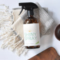 Bottle of 'Shiny Spray' with wooden bowls and a cloth on a light background
